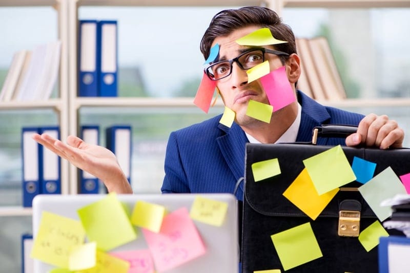 overworked businessman with post-it notes covering his face